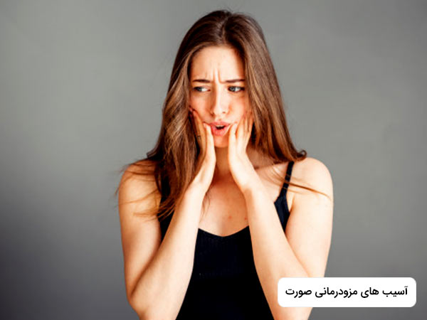 خانمي که يک تاپ سياه به تن دارد، نسبت به عوارض مزوتراپی صورت نگران است