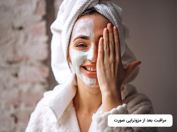خانم به دور سر خود يکک حوله پيچيده است. او به صورت خود کرم ماليده و با يک دست جلوي نصف صورت خود را پوشانده است.