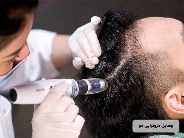 خانم پزشکي، در حال استفاده از تجهيزات مزوتراپي براي انجام مزوتراپي مو براي آقاي روي تخت مي باشد.