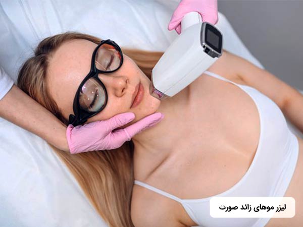 خانمي روي تخت دراز کشيده و چشمان خود را بسته است. پزشک در حال رفع موهاي ناخواسته چانه او با استفاده از روش ليزر موهاي زائد مي باشد.