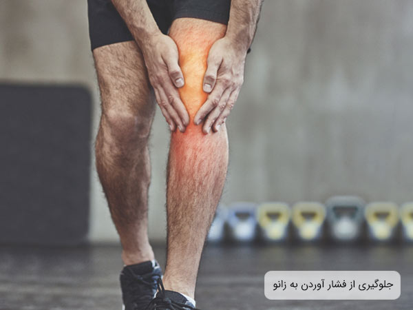 تصويری از زانوی يک مرد که با دست هايش زانويش را فشار می دهد.