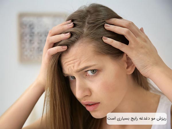 يک خانم جوان که با نگرانی به موهای جلوی سر خود نگاه مي کند.