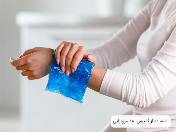 يک خانم کمپرس سرد آبی رنگ را روی دست خود گذاشته است.
