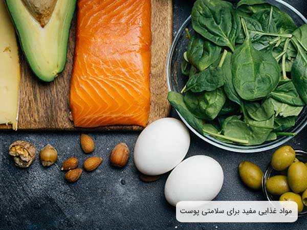 چند ماده غذايی از جمله سالمون، تخم مرغ، آواکادو و اسفناج که براي سلامتی پوست مفيد هستند در کنار هم.