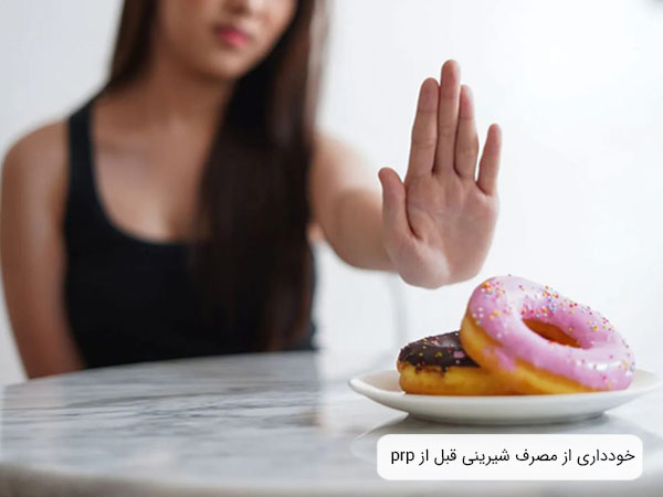 يک خانم که از مصرف شيرينی هايی که جلويش است امتناع ميکند.