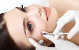 تزريق کوکتل مزوتراپی روی صورت يک خانم جوان توسط پزشک.