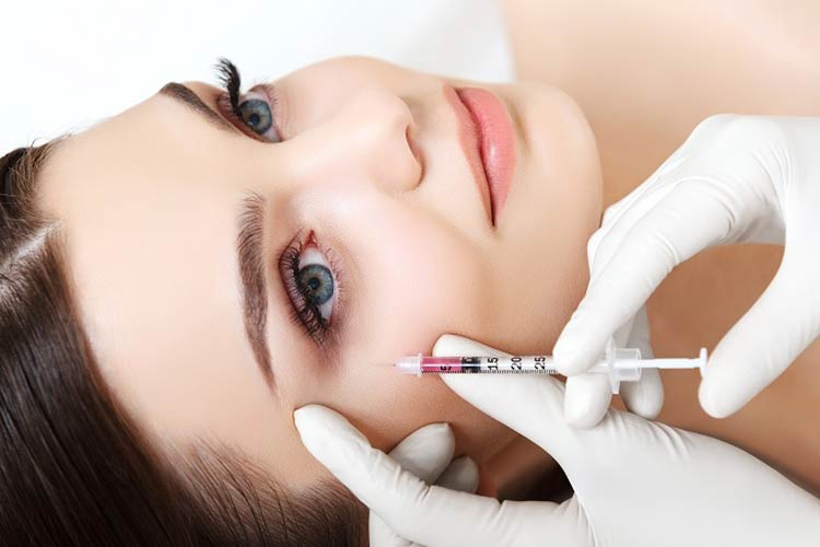 تزريق کوکتل مزوتراپی روی صورت يک خانم جوان توسط پزشک.