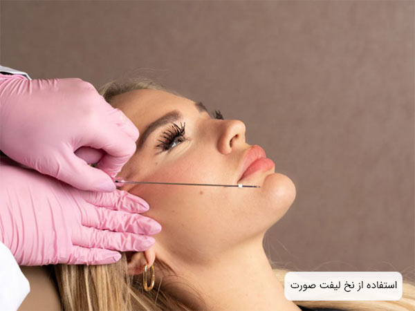 پزشک يک عدد نخ ليفت را در کنار صورت يک خانم نگه داشته است.