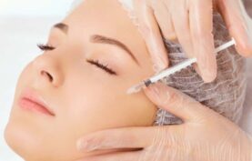 انجام مزوتراپی زیر چشم روی صورت یک خانم توسط پزشک با پس زمینه سفید.