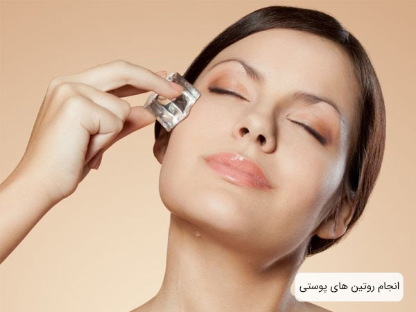 يک خانم جوان با پوست صاف و سالم که يک شيشه کوچک را روي صورت خود قرار داده است با پس زمينه کرمي رنگ.