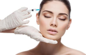 انجام مزوتراپی روی صورت یک خانم جوان توسط پزشک در پس زمینه سفید.