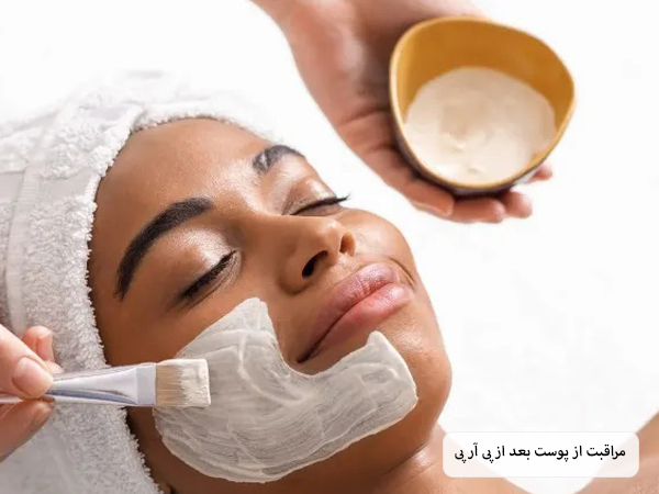 خانمی در حال استفاده از نوعی ماسک طبیعی سفید رنگ روی صورت خود است.