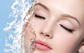 آبرسانی پوست صورت یک خانم جوان در پس زمینه آبی رنگ.