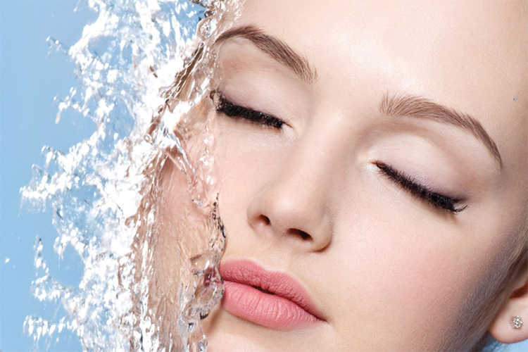 آبرسانی پوست صورت یک خانم جوان در پس زمینه آبی رنگ.